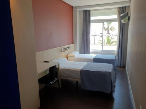 a hotel room with two beds and a desk and a window at El Globo in Valencia
