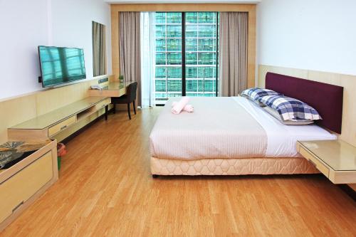 a bedroom with a bed and a desk and a television at Bernard Holiday Home @ Imperial Suites Kuching in Kuching