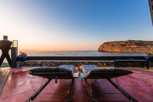 a view of the ocean from a balcony with two stools at Villa Menelaos in Mochlos