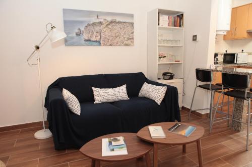 a living room with a black couch and two tables at Casa Sto. António in Zambujeira do Mar
