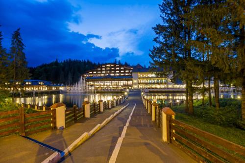 a bridge over a river at night with buildings at Aurelius Imparatul Romanilor Hotel & SPA in Poiana Brasov