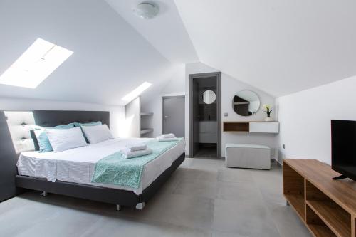 a bedroom with a bed and a flat screen tv at Saint Lucas Suites in Nea Potidaea