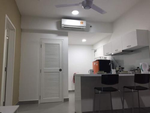 a kitchen with white cabinets and a counter with stools at Mayzi Holiday Home @ Cyberjaya in Cyberjaya