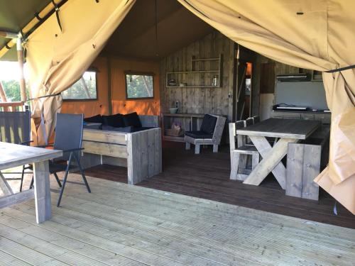 um quarto com uma tenda com uma mesa e cadeiras em Safaritent 't Kwedammertje em Kwadendamme