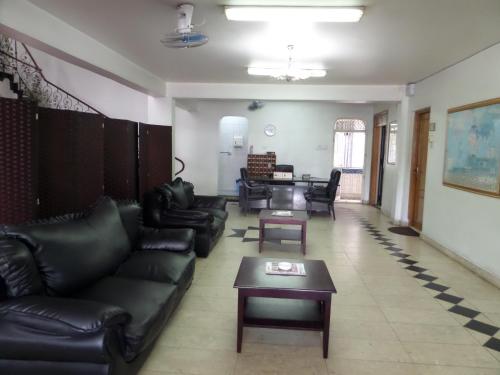 a living room with black leather couches and a table at Sophia Hotel in Dar es Salaam