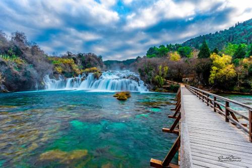 a bridge over a river with a waterfall at House Mellifera in Razvođe