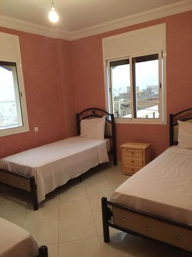 two beds in a room with two windows at Mirleft Trip in Mirleft
