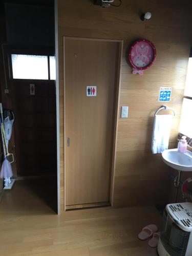 Una puerta en una habitación con lavabo y reloj en Ioki Station Guest House, en Aki