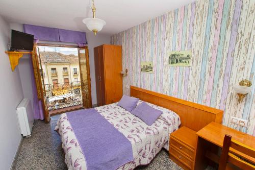a bedroom with a bed and a desk and a window at Hostal Plaza in Ciudad-Rodrigo