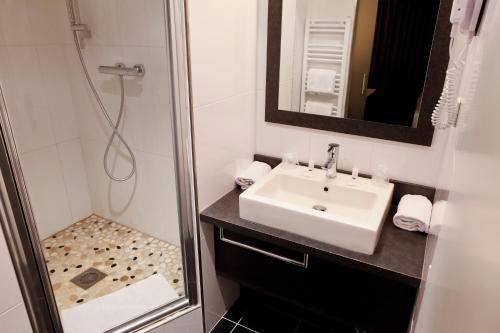 a bathroom with a sink and a shower at Kyriad Lyon Sud Sainte Foy in Sainte-Foy-lès-Lyon