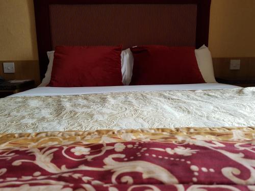 a bed with two red pillows on top of it at Shap Wells Hotel in Shap