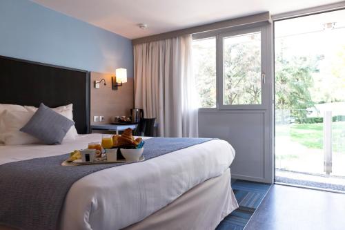 um quarto de hotel com uma cama com uma bandeja de comida em Kyriad Lyon Sud Sainte Foy em Sainte-Foy-lès-Lyon