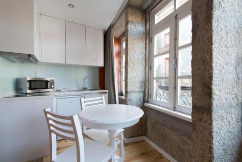 a small kitchen with a white table and a window at Casas do Loureiro in Porto