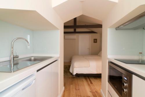 a kitchen with a sink and a bed in a room at Casas do Loureiro in Porto
