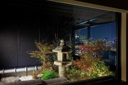a stone statue in front of a window with a city at Osaka View Hotel Honmachi in Osaka