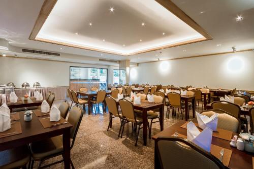 a dining room filled with tables and chairs at Airport Beach Hotel Phuket in Nai Yang Beach