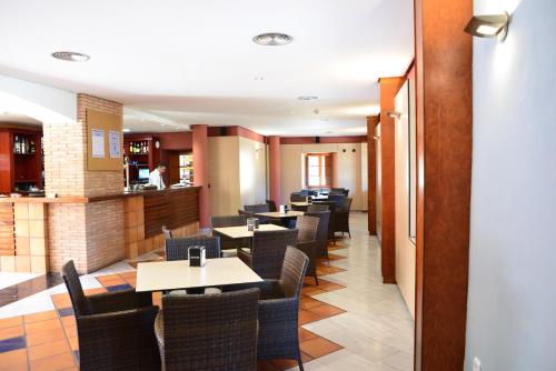 a restaurant with tables and chairs and a bar at Jardines de La Santa in Totana