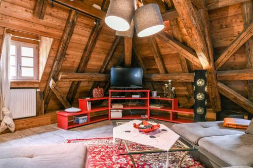 a living room with a couch and a tv in a log cabin at Porte des Pucelles in Ribeauvillé