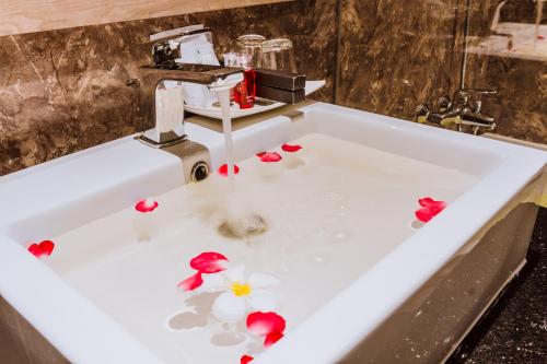 a sink with flower petals in the water at Airport Beach Hotel Phuket - SHA Extra Plus in Nai Yang Beach