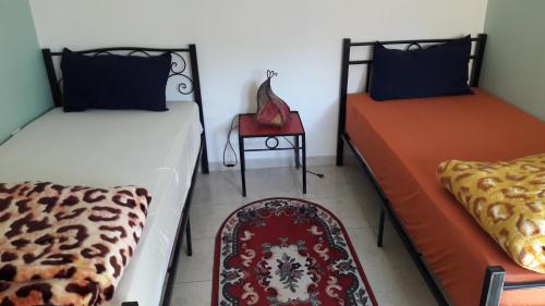 2 camas en una habitación con mesa y silla en Dar Diafa, en Agadir
