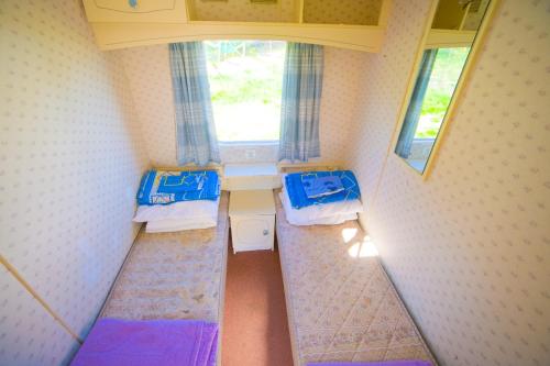 a small room with two beds and a window at Domki Holenderskie Red Ice in Władysławowo