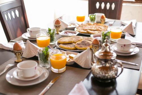 a table topped with plates of food and orange juice at Riad Fes Andalucia in Fès