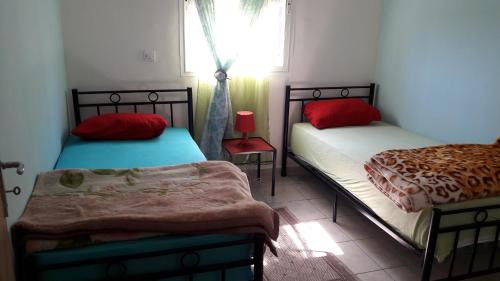 1 Schlafzimmer mit 2 Betten mit roten Kissen und einem Fenster in der Unterkunft Résidence Mogador in Agadir