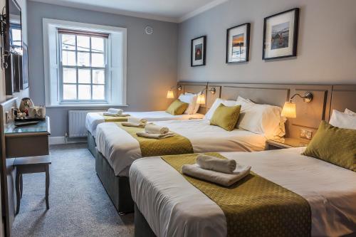 a hotel room with three beds with towels on them at The Bridge Tavern in Wicklow