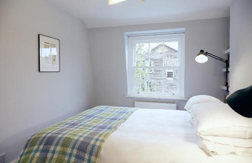a white bedroom with a bed and a window at Veeve - Angel Hideaway in London