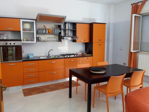 a kitchen with orange cabinets and a table and chairs at Casa Paradiso in Brindisi