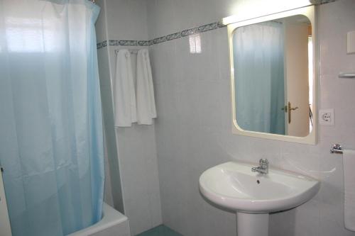 a white bathroom with a sink and a mirror at Apartamentos Astoria - Benidorm in Benidorm