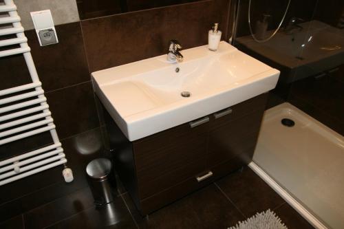 a bathroom with a white sink and a bath tub at Apartamenty Adalbert in Gdańsk