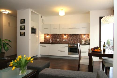 a kitchen and dining room with white cabinets and a table at Apartamenty Adalbert in Gdańsk