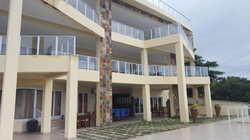 a large white building with a balcony and chairs at The Homestead Margate - South Africa in Margate