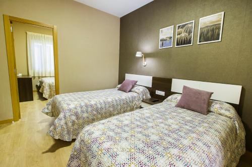 two beds in a hotel room with sidx sidx sidx sidx at Hospedería Castilla Plaza Mayor in Ciudad-Rodrigo