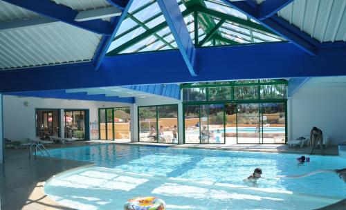 une grande piscine avec des gens dans l'eau dans l'établissement Cottages des Pins, à Saint-Hilaire-de-Riez