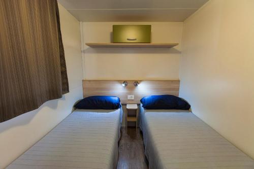 ソットマリーナにあるCamping Tredueのベッド2台、壁掛けテレビが備わる客室です。
