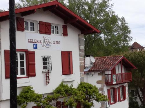 a white building with red shutters on it at Galerie d'art d'une ancienne mairie de 1783 in Espelette