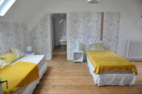 two beds in a room with wooden floors at Clairefontaine Chambre d'Hôtes in Angy