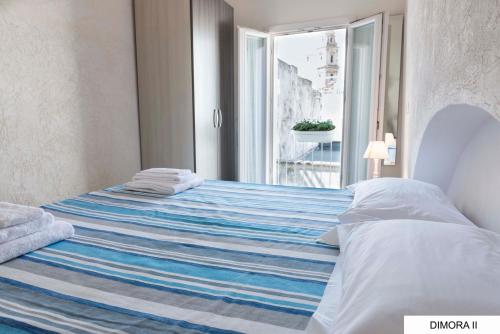 a bedroom with a bed with a blue and white blanket at La Dimora sull'Arco in Monopoli