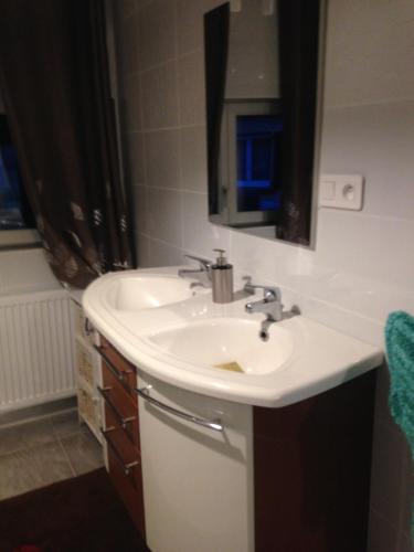 uma casa de banho com um lavatório branco e um espelho. em cosy logement à la campagne em Marthille