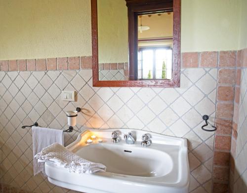 a bathroom with a white sink and a mirror at Residenza Storica Casale Pozzuolo in Cinigiano