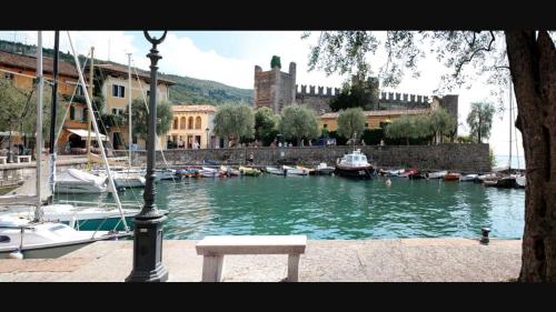 a bench sitting next to a river with boats at Suite La Castellana in Torri del Benaco