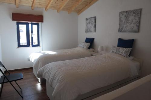 two beds in a room with white walls at Casa Sto. António in Zambujeira do Mar