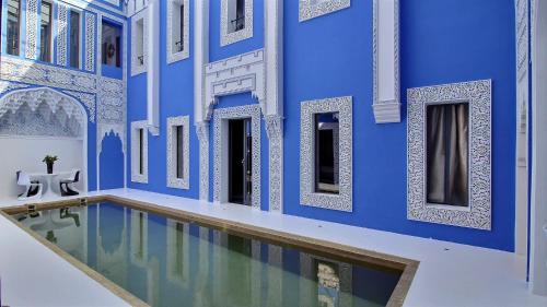 a blue building with a swimming pool in front of it at Riad Goloboy in Marrakech