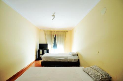 a small room with two beds and a window at Suites & Apartments DP VFXira in Vila Franca de Xira