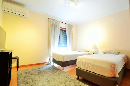 a bedroom with two beds and a window at Suites & Apartments DP VFXira in Vila Franca de Xira