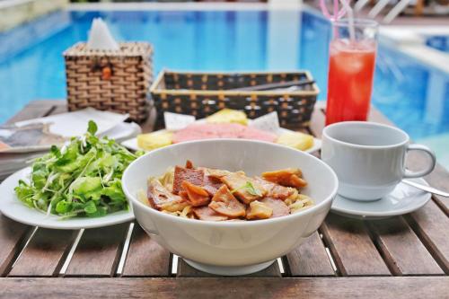 a bowl of food on a table with a salad and a drink at Riverside Hamlet Homestay & Villa in Hoi An
