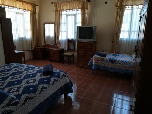 a hotel room with two beds and a television at Apartamento Golden in Cochabamba