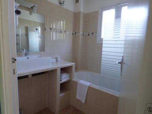 a bathroom with a tub and a sink and a shower at Logis Hôtels La Crémaillère in Saint-Bonnet-en-Champsaur